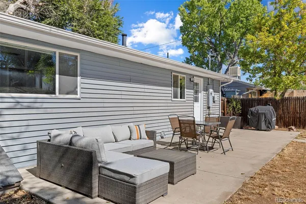 a view of a patio with couches and table and chairs with wooden fence and plants