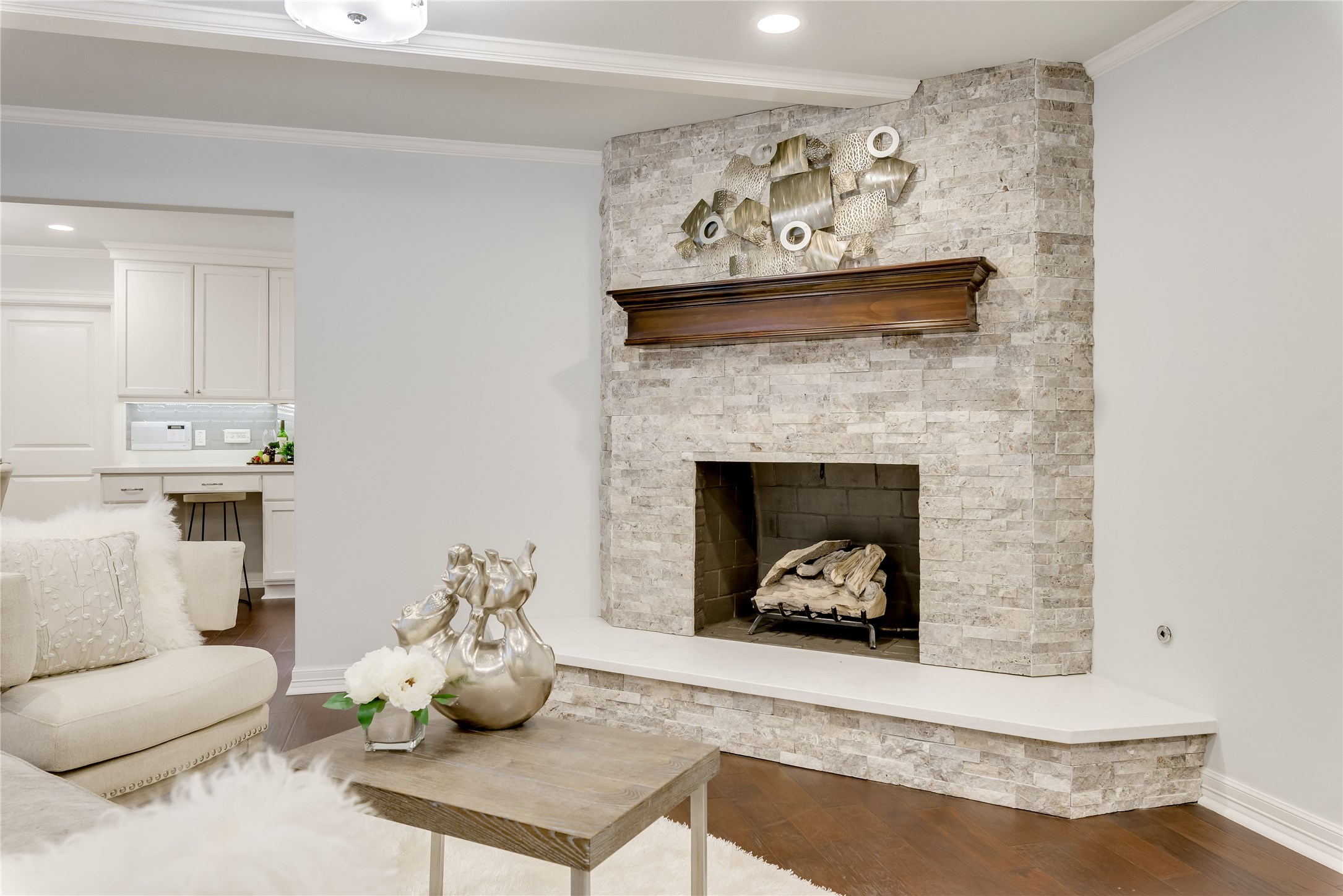 1010 Thornton Road Houston, TX 77018 - Photo 6 of 27 A cozy living room features a stylish stone fireplace with a wooden mantel. The room is bright and inviting, with an open view into a modern kitchen, creating a seamless flow between spaces.