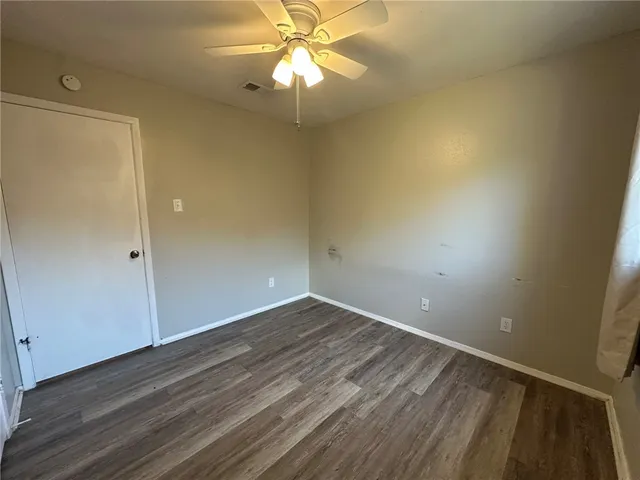 en empty room with wooden floor and fan
