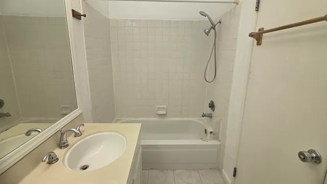 a bathroom with a granite countertop bathtub shower sink vanity and a toilet