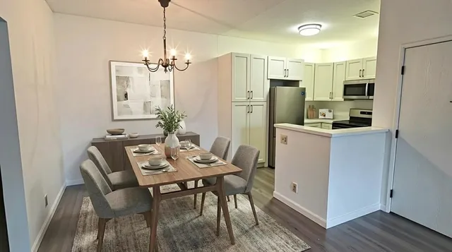 a kitchen with stainless steel appliances a dining table chairs and refrigerator