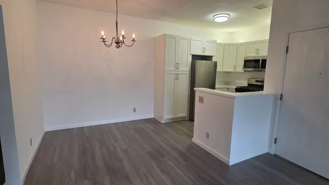 a view of a kitchen with refrigerator and wooden floor