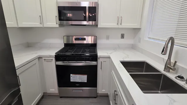 a kitchen with white cabinets and black appliances