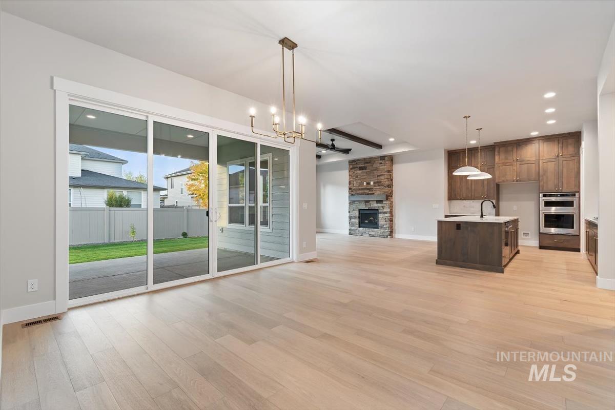 2147 East Blakehurst Avenue Kuna, ID 83634 - Photo 15 of 43 Unfurnished dining area with a stone fireplace, a chandelier, light wood finished floors, and recessed lighting