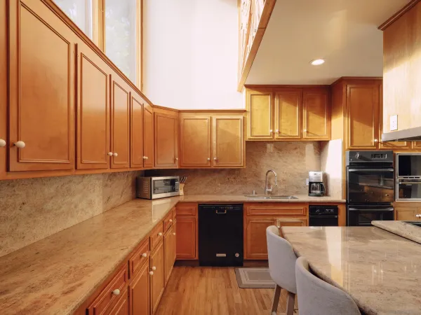 a kitchen with stainless steel appliances granite countertop a sink a stove a refrigerator cabinets and a dining table