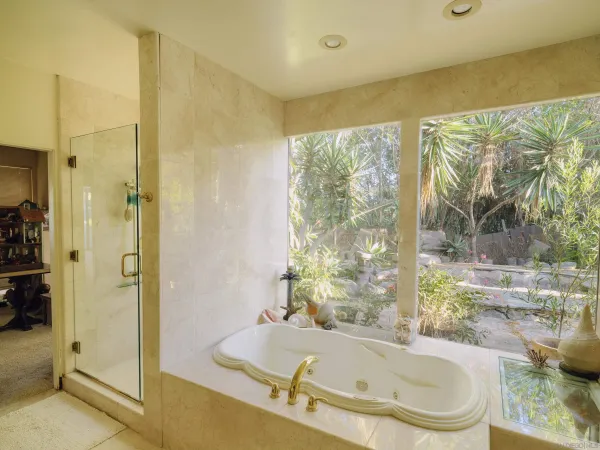 a bathroom with a granite countertop tub sink and glass door