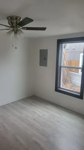 an empty room with a window and a ceiling fan