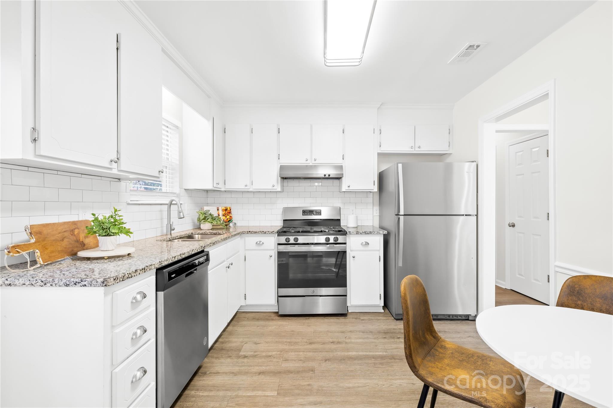 11816 Park Road Charlotte, NC 28226 - Photo 12 of 26 a kitchen with stainless steel appliances granite countertop a refrigerator a stove a sink dishwasher and white cabinets with wooden floor