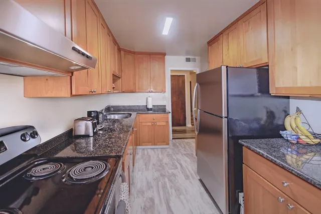 a kitchen with stainless steel appliances granite countertop wooden floors a stove a microwave and wooden floors