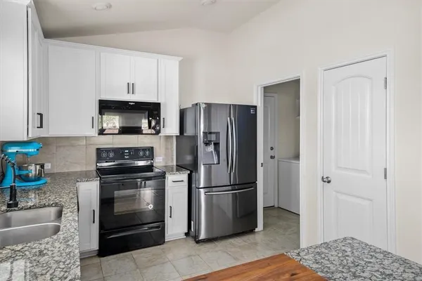 a kitchen with stainless steel appliances granite countertop a refrigerator a stove a sink and a microwave