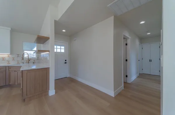an empty room with kitchen view and wooden floor