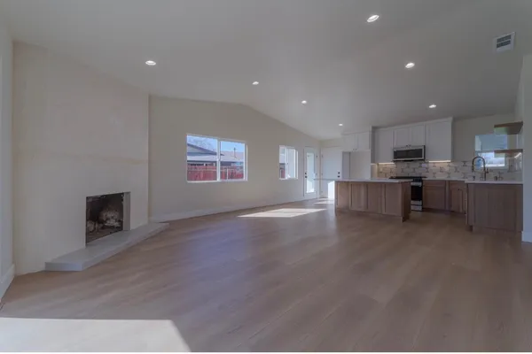 a view of a kitchen with a sink wooden cabinets and a fireplace