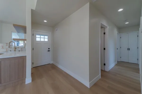 a view of an empty room with wooden floor and a bathroom