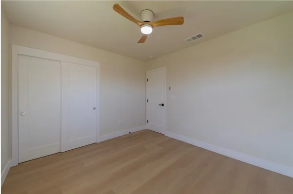 an empty room with ceiling fan and window