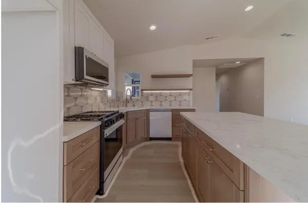 a kitchen with stainless steel appliances granite countertop a stove top oven a sink and a microwave