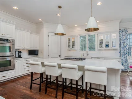 a kitchen with stainless steel appliances kitchen island granite countertop a stove a sink a dining table and chairs with wooden floor