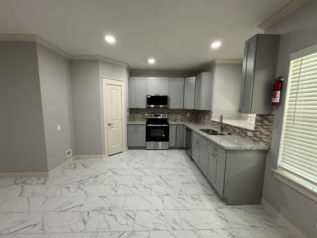 a large kitchen with stainless steel appliances granite countertop a stove and a sink