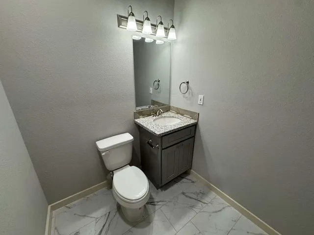 a bathroom with a granite countertop toilet and a sink