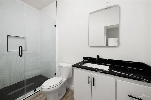 a bathroom with a granite countertop sink a toilet a mirror and shower