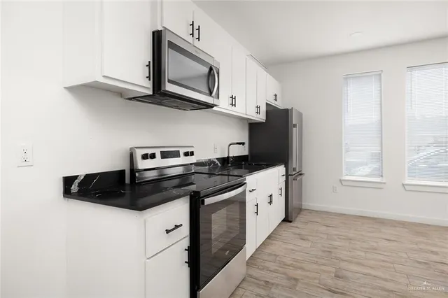 a kitchen with stainless steel appliances granite countertop white cabinets a stove a sink and dishwasher