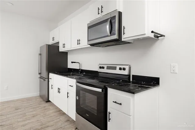 a kitchen with stainless steel appliances a stove a microwave a sink and cabinets