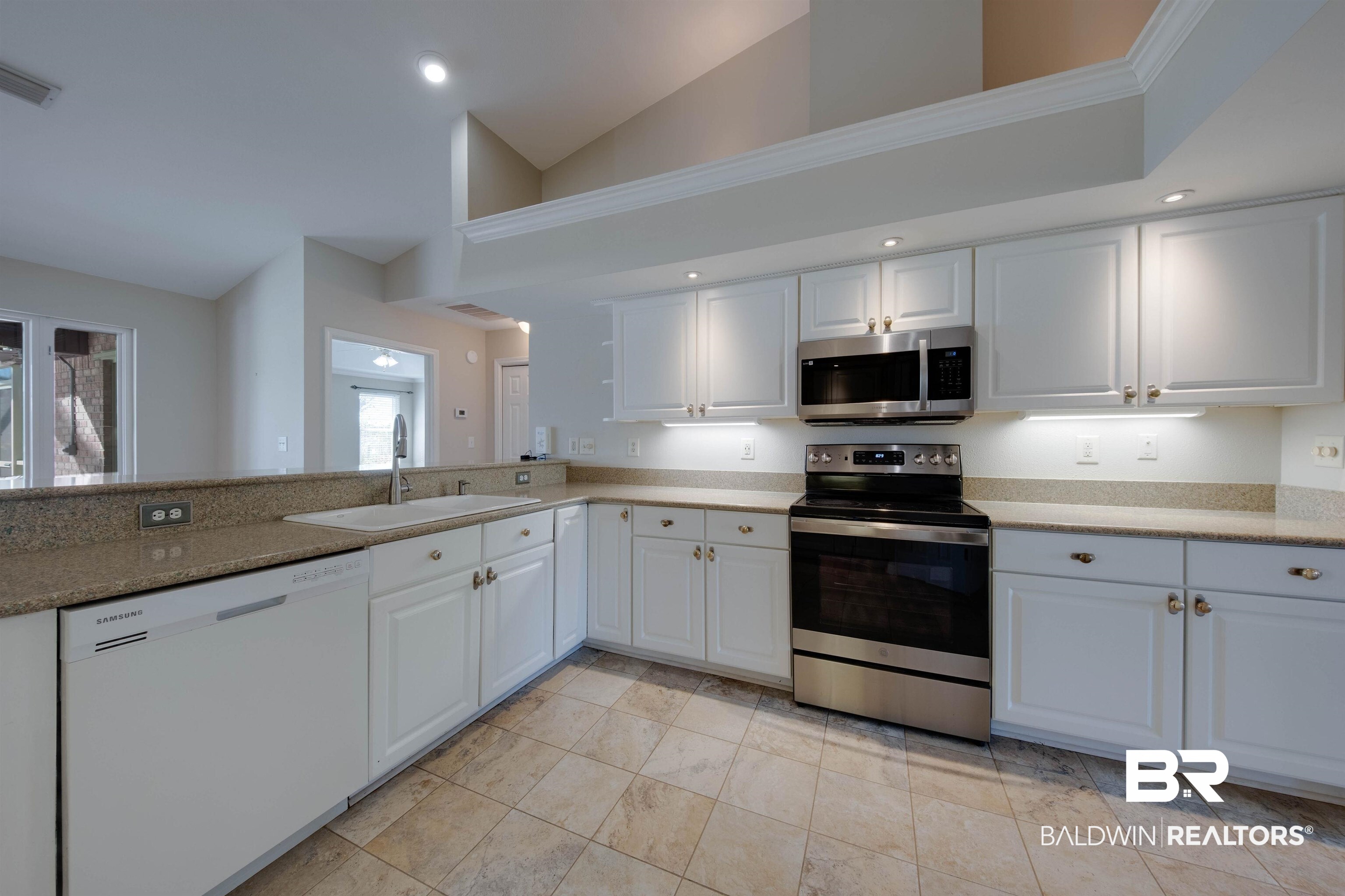 9462 Lakeview Drive Foley, AL 36535 - Photo 14 of 50 Kitchen featuring kitchen peninsula, white cabinetry, high vaulted ceiling, sink, and stainless steel appliances