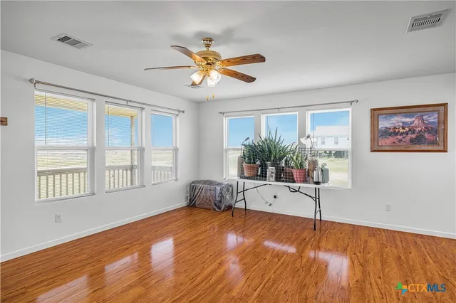 a view of a kitchen with furniture a ceiling fan and wooden floor