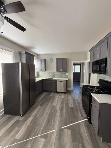 a view of empty room with wooden floor and fan