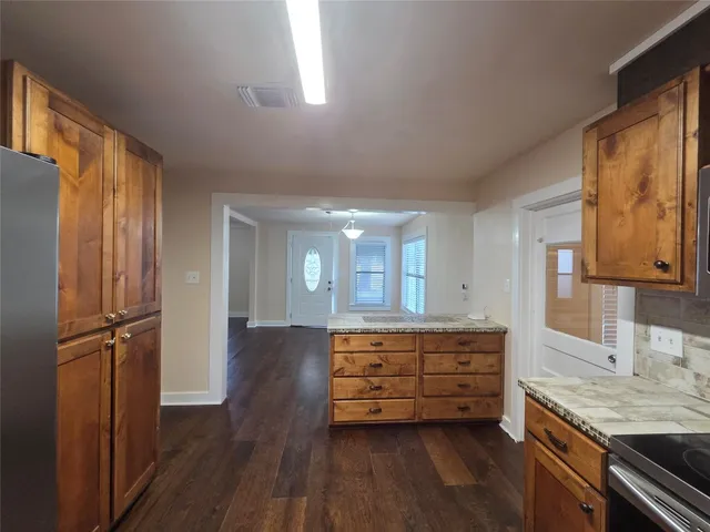 a kitchen with stainless steel appliances granite countertop a refrigerator a sink and wooden cabinets