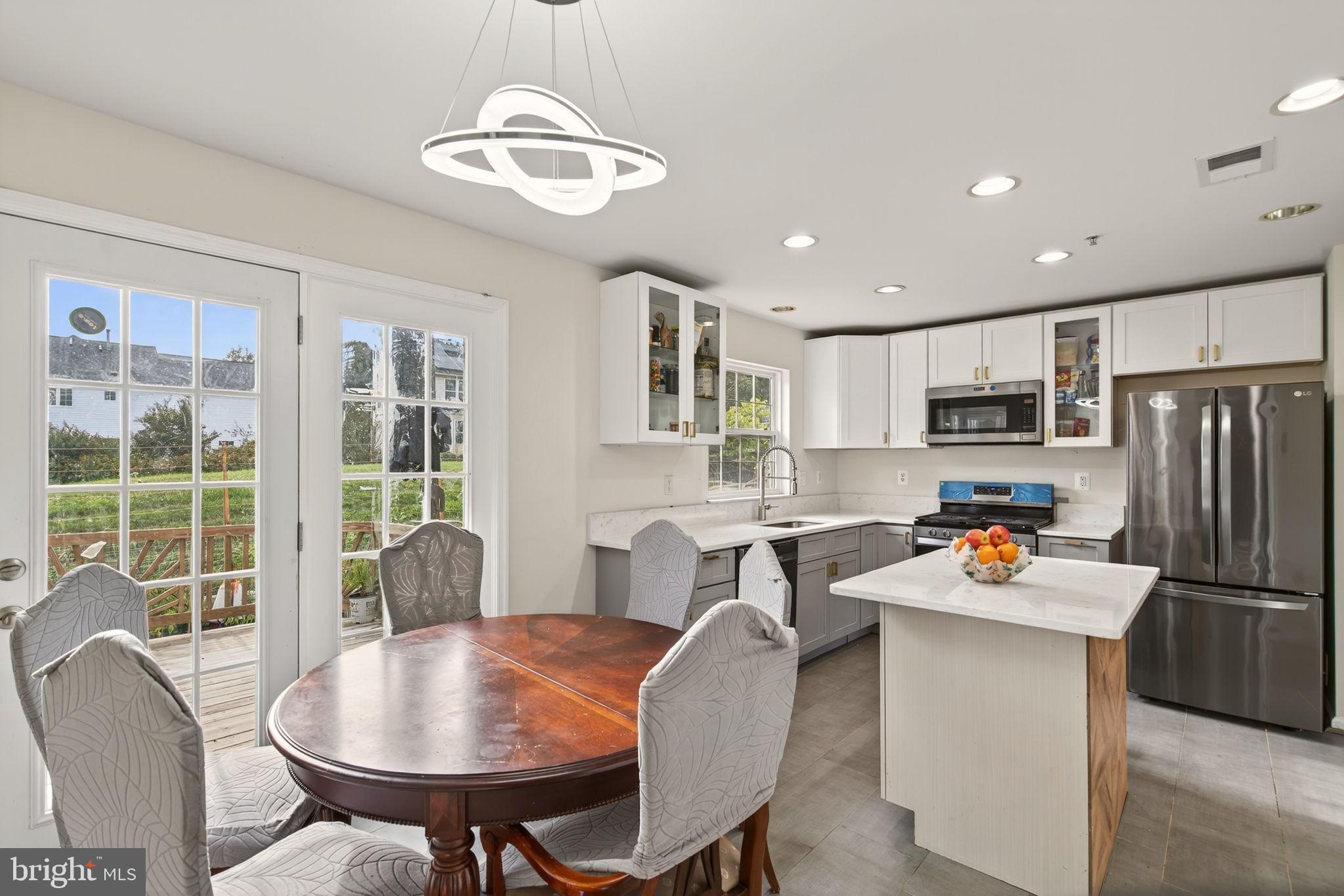 6903 Bock Road Fort Washington, MD 20744 - Photo 15 of 62 a kitchen with a refrigerator a stove a sink dishwasher a dining table and chairs with wooden floor