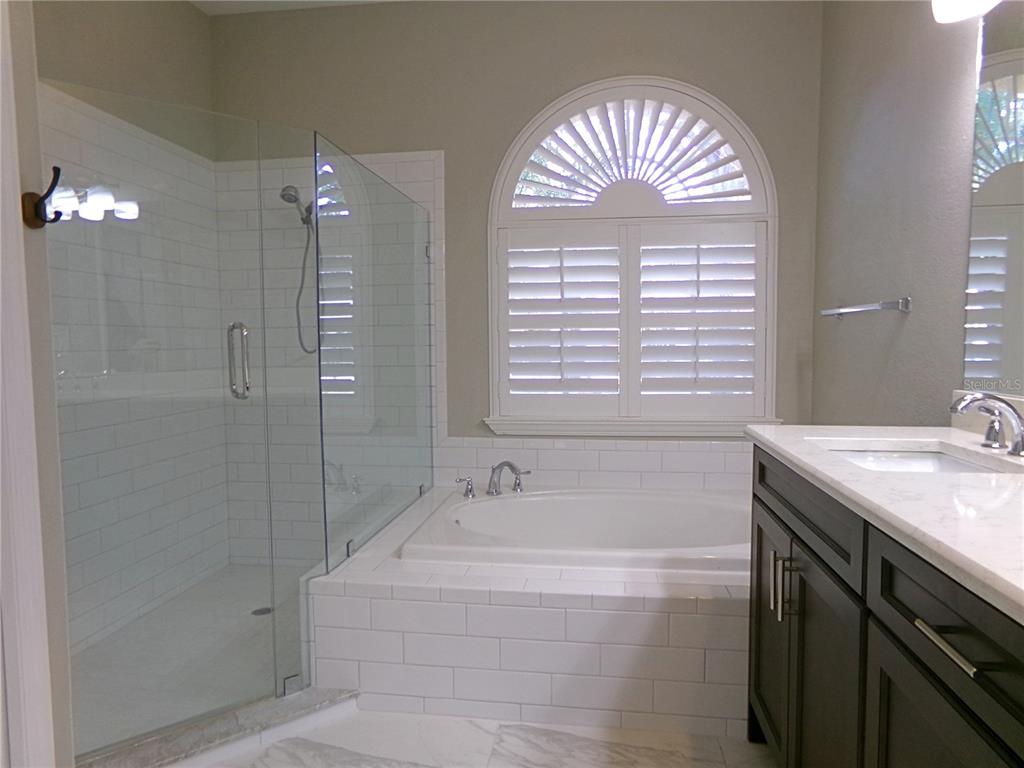 3603 Cypress Meadows Road Tampa, FL 33624 - Photo 19 of 33 a spacious bathroom with a granite countertop tub a sink and a shower