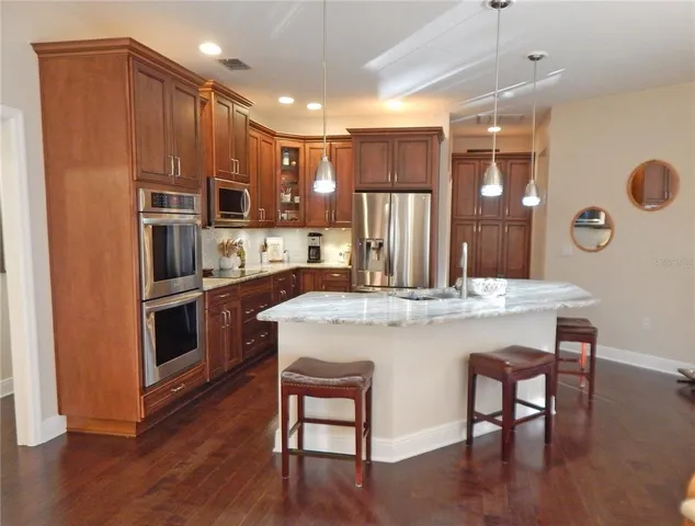 a kitchen with kitchen island a refrigerator and a stove top oven