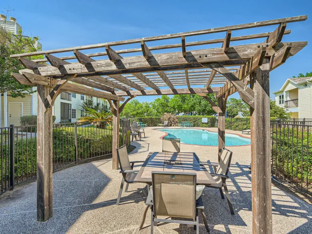 a view of a patio with table and chairs under an umbrella with a small yard