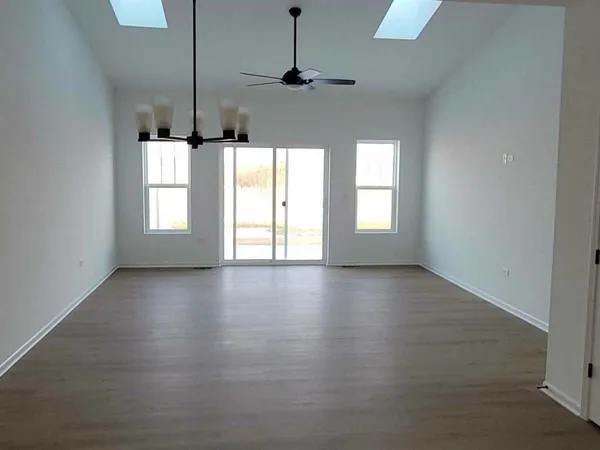an empty room with windows and ceiling fan