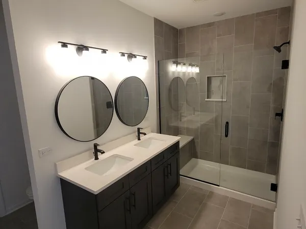 a bathroom with a double vanity sink mirror and shower