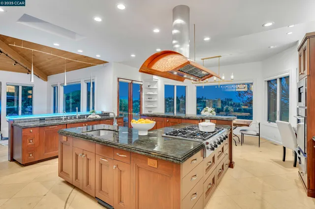 a kitchen with stainless steel appliances granite countertop a stove a sink and a dining table