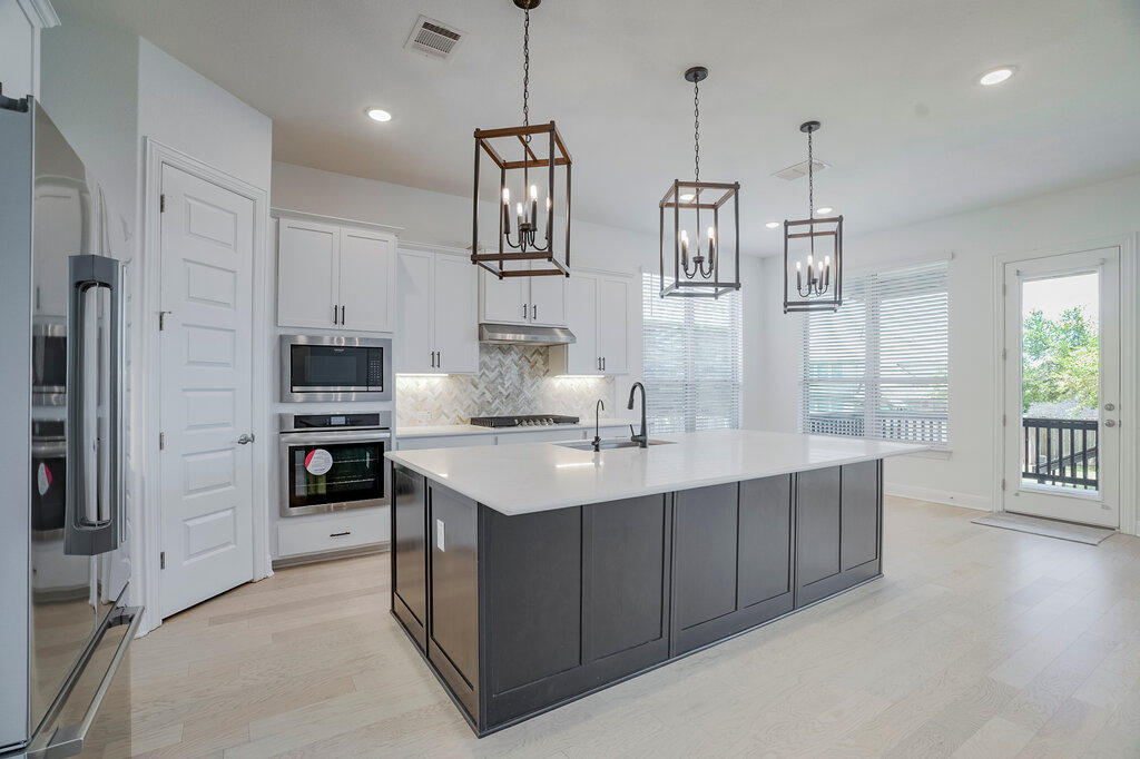 2920 Hadley Way Leander, TX 78641 - Photo 4 of 20 An inviting kitchen with a central island and contemporary lighting fixtures, offering direct access to an outdoor area.