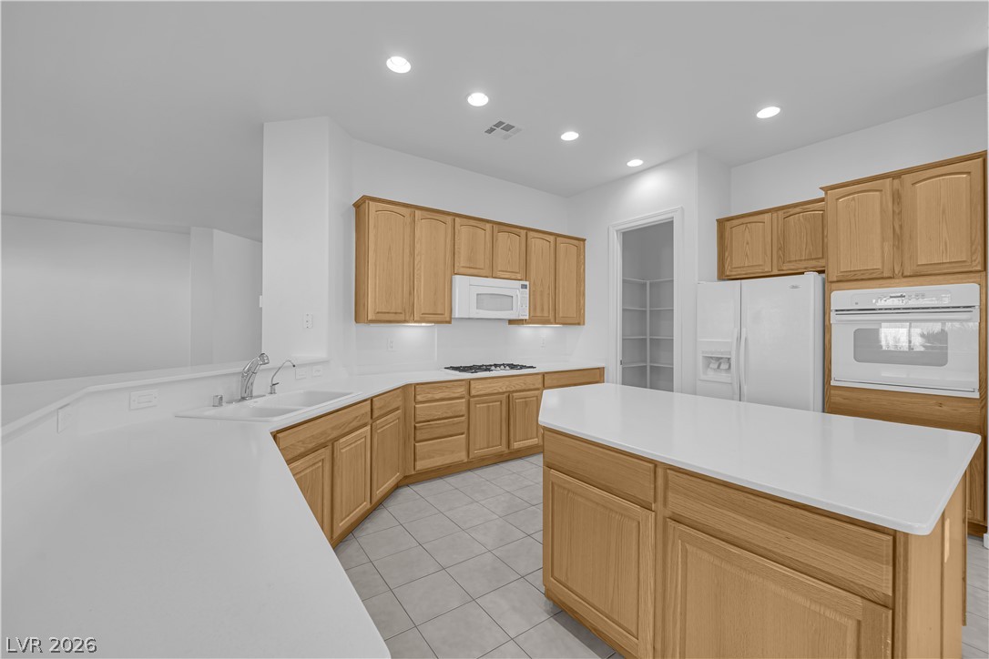 2184 Waterton Rivers Drive Henderson, NV 89044 - Photo 9 of 53 Island Kitchen boasts Corian Countertops, Walk-In Pantry, Recessed Lighting, Breakfast Bar, Large Nook, Tile Flooring, Refrigerator, Gas Cooktop, Built-In Oven, Microwave and Dishwasher