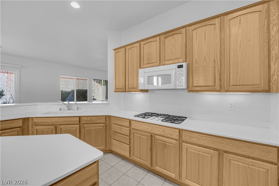 2184 Waterton Rivers Drive Henderson, NV 89044 - Photo 12 of 53 Island Kitchen boasts Corian Countertops, Walk-In Pantry, Recessed Lighting, Breakfast Bar, Large Nook, Tile Flooring, Refrigerator, Gas Cooktop, Built-In Oven, Microwave and Dishwasher