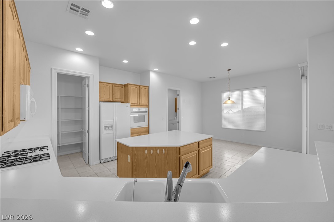 2184 Waterton Rivers Drive Henderson, NV 89044 - Photo 14 of 53 Island Kitchen boasts Corian Countertops, Walk-In Pantry, Recessed Lighting, Breakfast Bar, Large Nook, Tile Flooring, Refrigerator, Gas Cooktop, Built-In Oven, Microwave and Dishwasher