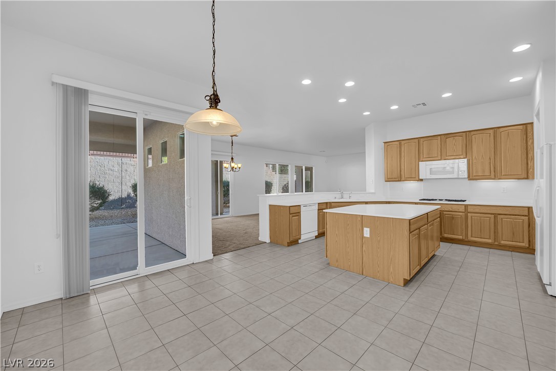 2184 Waterton Rivers Drive Henderson, NV 89044 - Photo 7 of 53 Island Kitchen boasts Corian Countertops, Walk-In Pantry, Recessed Lighting, Breakfast Bar, Large Nook, Tile Flooring, Refrigerator, Gas Cooktop, Built-In Oven, Microwave and Dishwasher