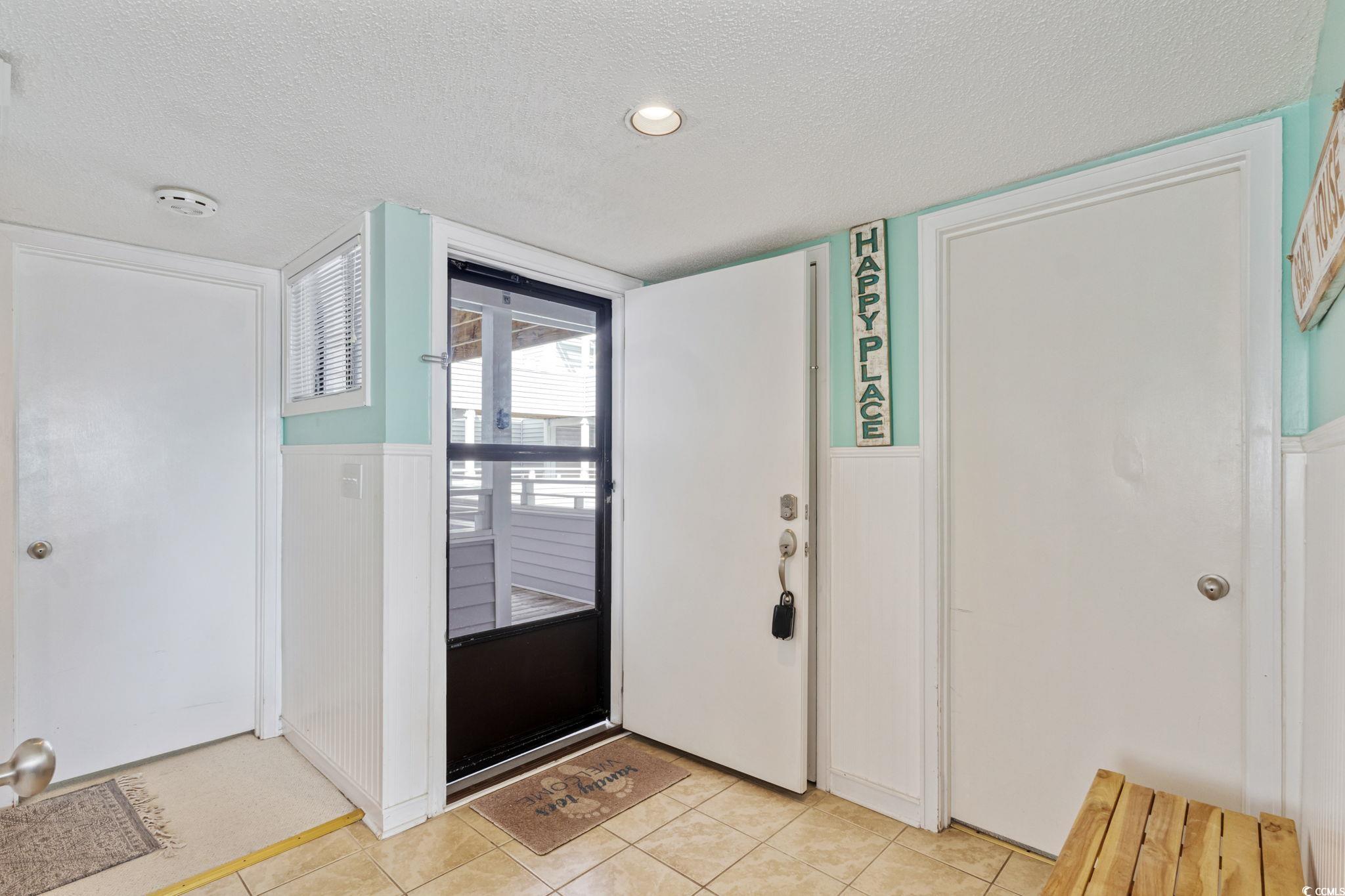 351 Lake Arrowhead Road, Unit 2206 Myrtle Beach, SC 29572 - Photo 3 of 40 Foyer entrance with a textured ceiling, a wainscoted wall, and light tile patterned floors