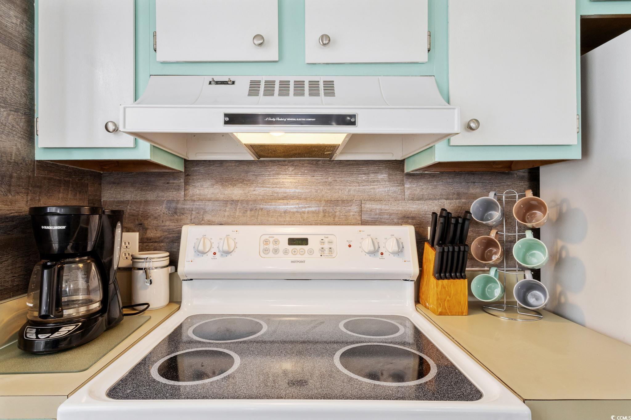 351 Lake Arrowhead Road, Unit 2206 Myrtle Beach, SC 29572 - Photo 10 of 40 Kitchen featuring under cabinet range hood, white range with electric cooktop, tasteful backsplash, light countertops, and white cabinets