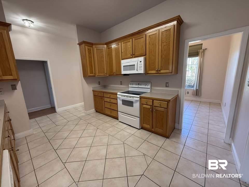 10428 South Side Loop Fairhope, AL 36532 - Photo 16 of 28 Kitchen featuring light tile patterned floors, light countertops, white appliances, and brown cabinetry
