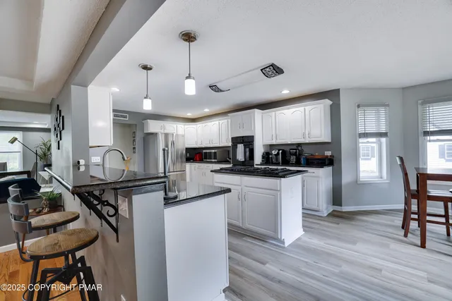 a kitchen with stainless steel appliances granite countertop a refrigerator oven a sink dishwasher and white cabinets with wooden floor