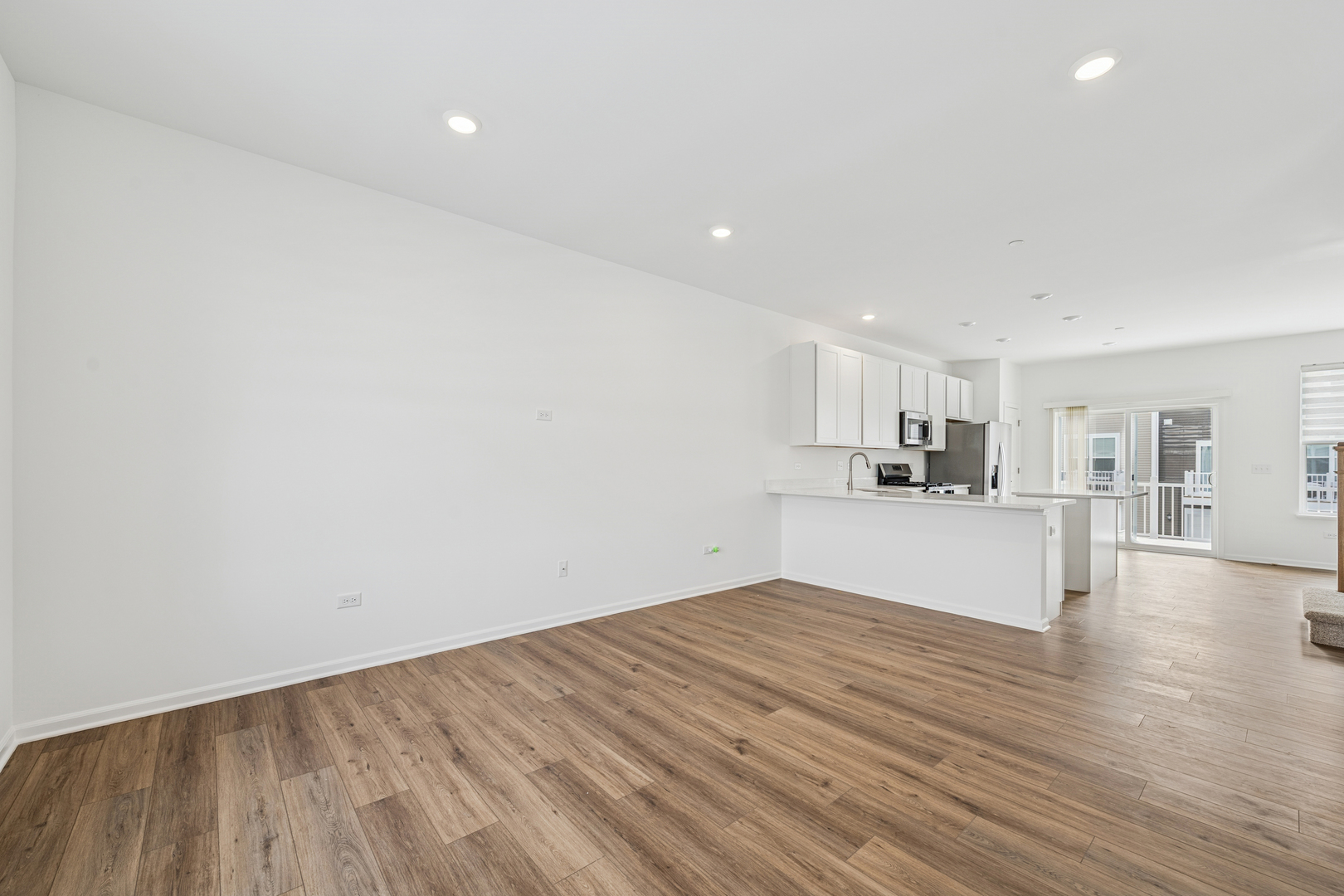 12312 Tinsley Street Huntley, IL 60142 - Photo 7 of 24 a view of empty room with wooden floor and kitchen