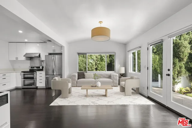a living room with couches a coffee table and kitchen view with wooden floor