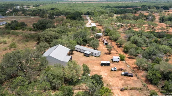 an aerial view of residential house with outdoor space and trees all around