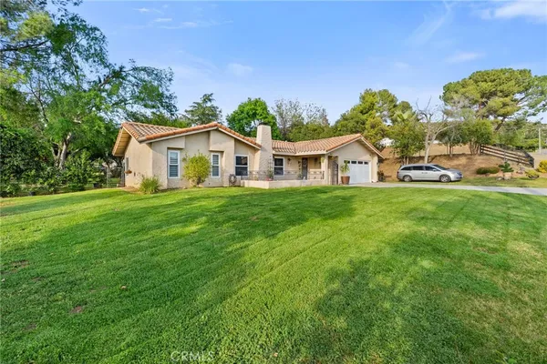 a view of a house with a big yard and large trees