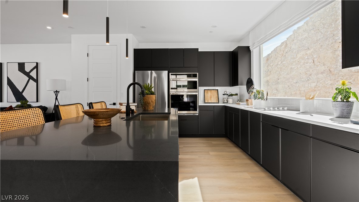 11099 Socrates Ridge Street Las Vegas, NV 89141 - Photo 6 of 29 This modern kitchen features sleek dark cabinetry, premium appliances, and abundant natural light.